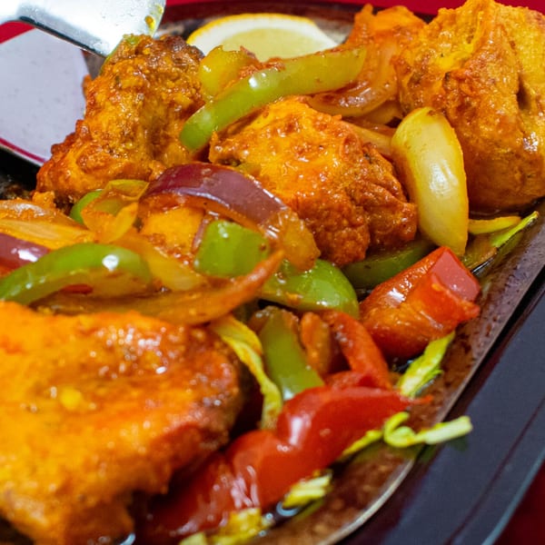 Sizzling Indian chicken tikka with bell peppers and onions, served on a hot platter.
